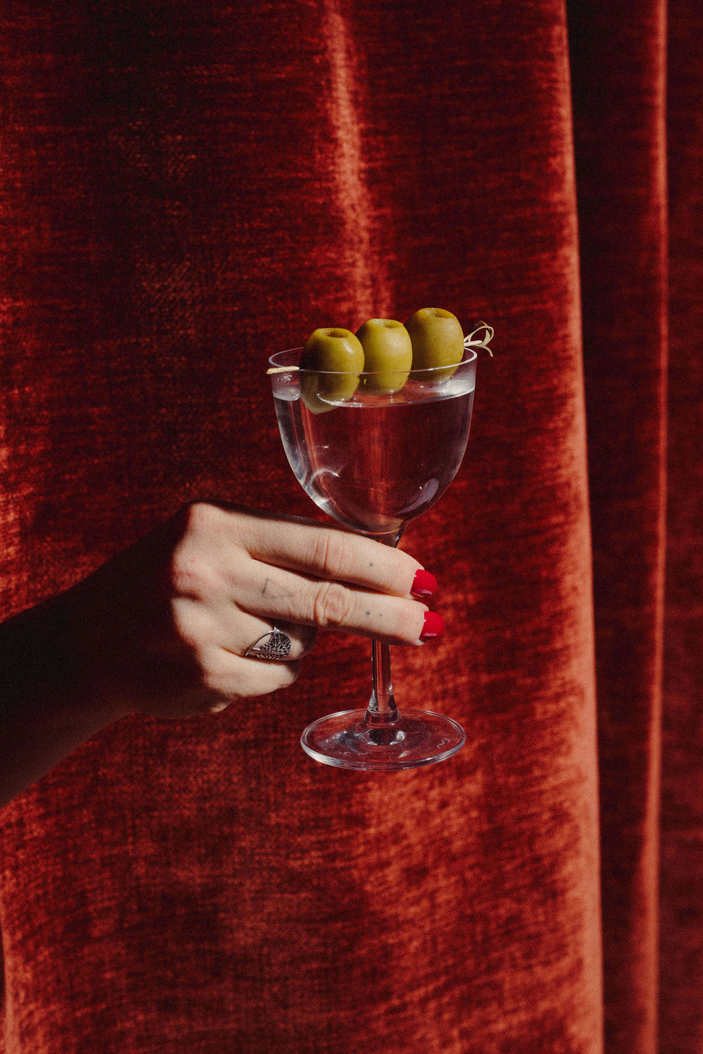 A martini glass set against red velvet curtains at SOHO
