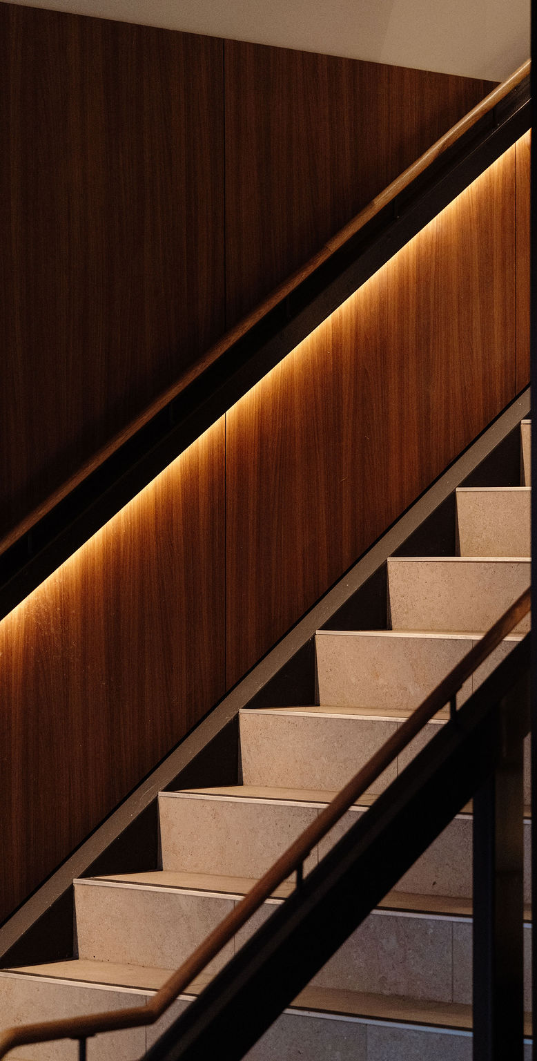 The stone staircase and lit timber handrail leading up to SOHO on Level 1 of Hotel Jardin